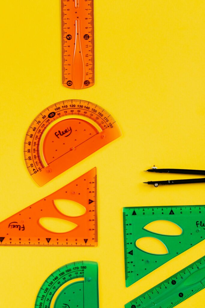 Colorful geometry tools and stationery set on a vibrant yellow background, ideal for educational themes.