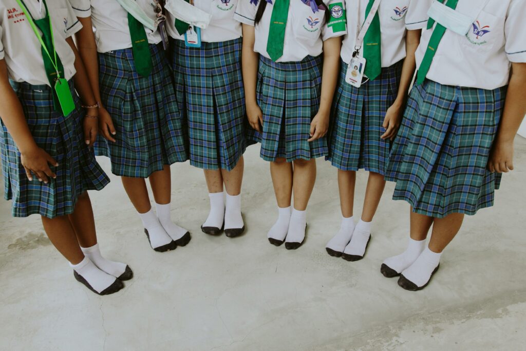 Low angle view of children in school uniforms standing in a row indoors.