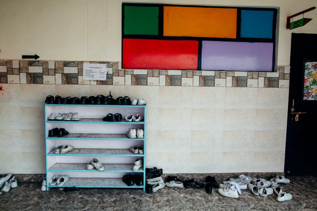 A school hallway with a colorful wall and neat shoe rack arrangement.