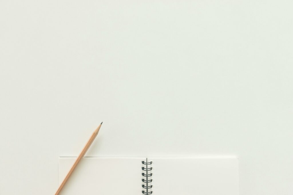 A top view of a spiral notebook with pencil on a neutral light background, ideal for creative workspaces.