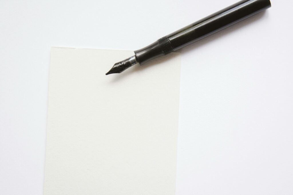 A close-up image of an elegant fountain pen resting on blank white paper, perfect for writing themes.