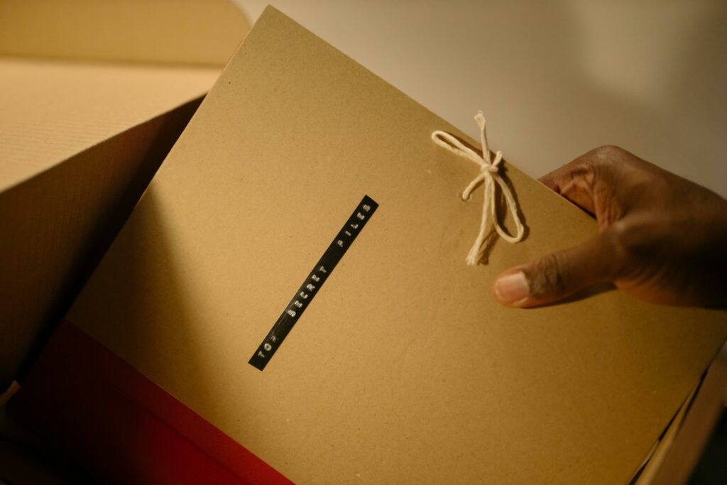 Close-up of hand holding top secret document folder in a box.