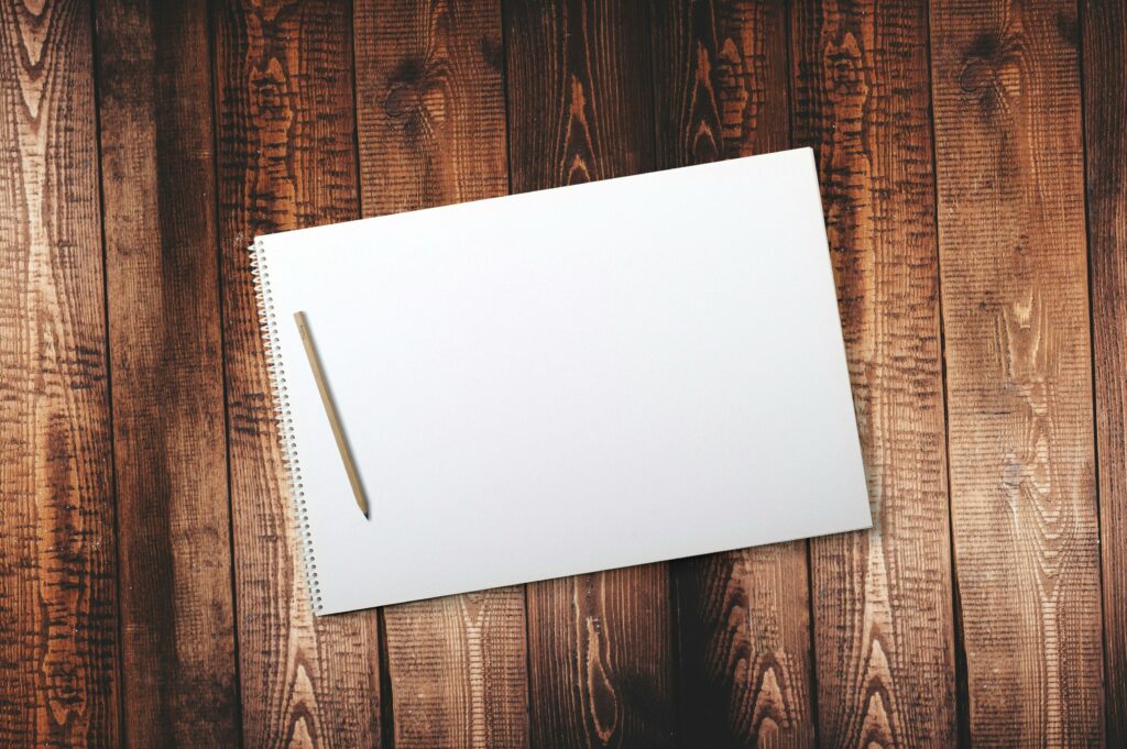 Open blank spiral notebook with pencil on wood table, perfect for creative or educational projects.